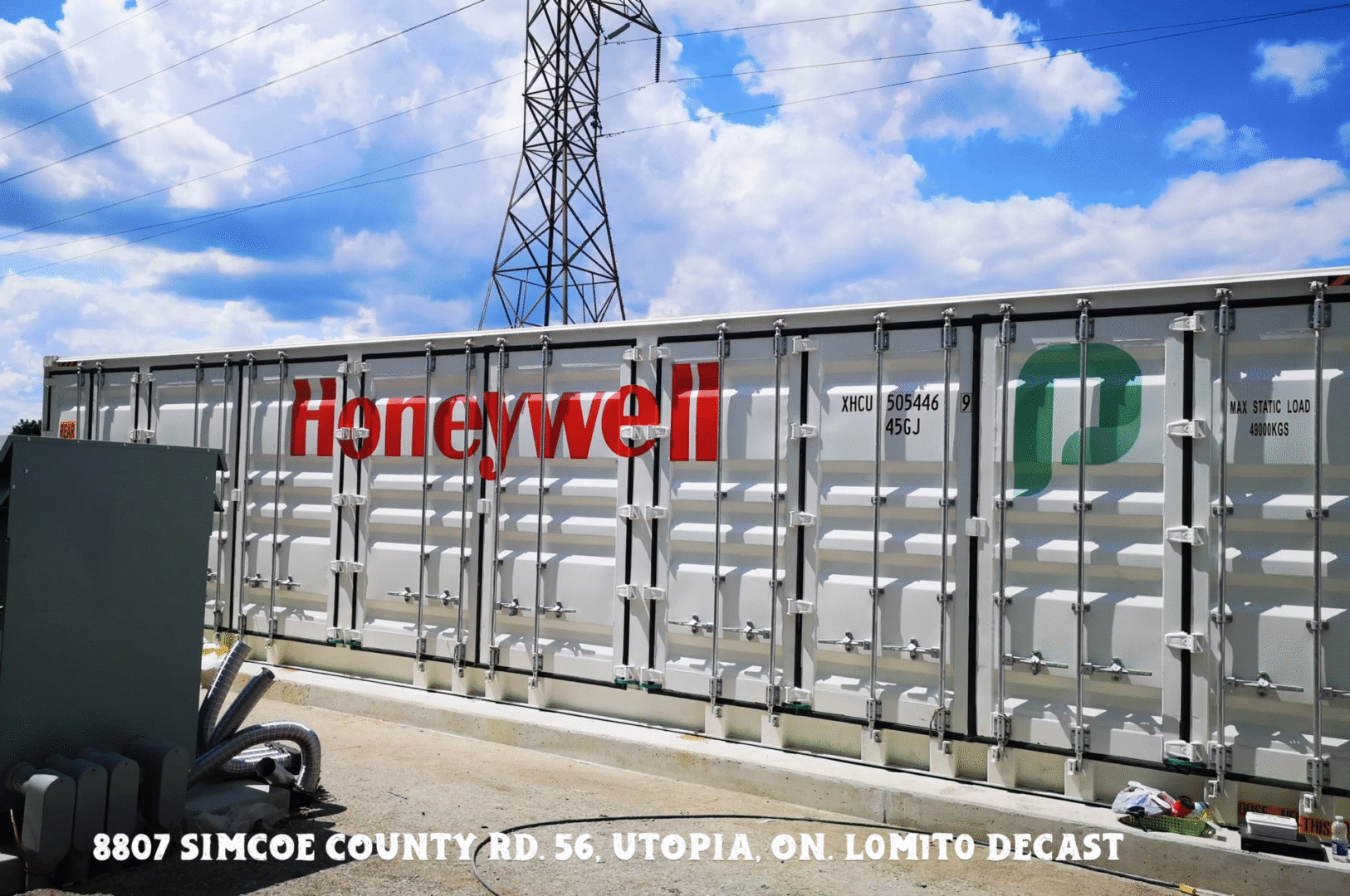A large Honeywell shipping container under a blue sky with power lines.