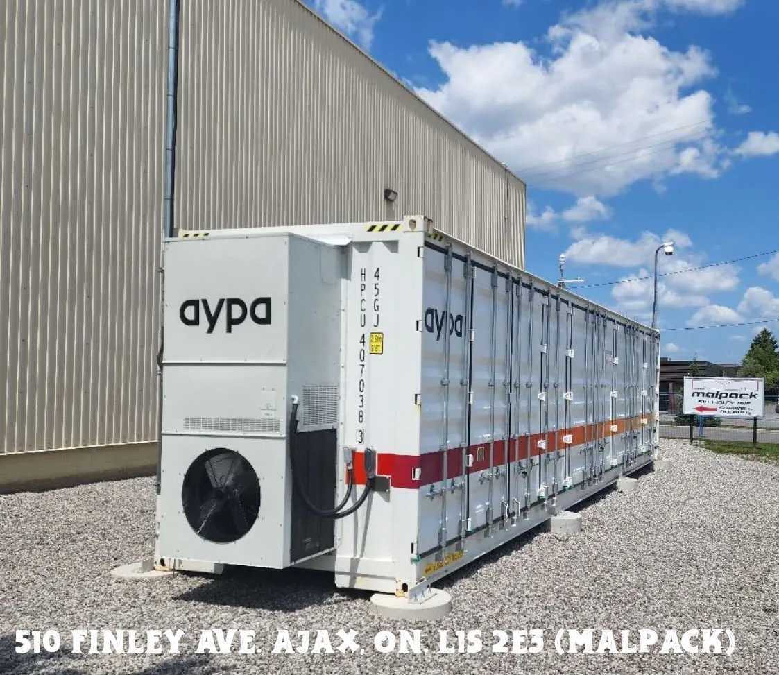 Large industrial refrigeration units outside a warehouse under a blue sky.