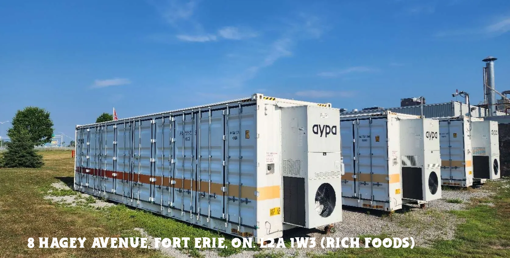 Large shipping containers stacked under a blue sky at a port.